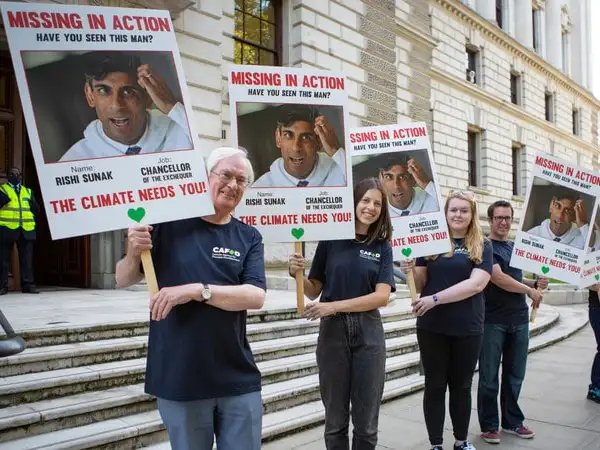 UK - Westminster - CAFOD supporters holding Rishi Sunak climate leadership placards outside the Treasury